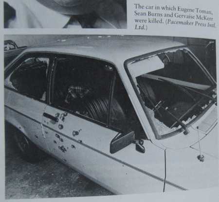Black and white photograph of a small car showing a dozen or so holes in the driver's door towards the rear of the car (ie close to the back of the driver's seat).  Almost all the glass in the windows is missing