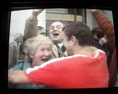 Four people looking jubilant, two about to embrace, some arms still in air